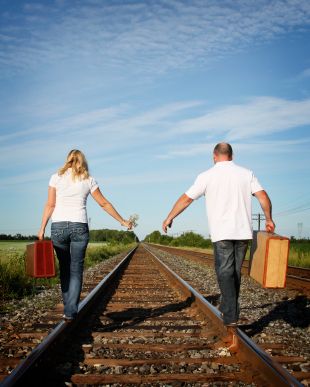 couple walking on opposite sides of the railroad tracks