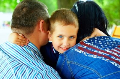 kid smiling to hug his parents