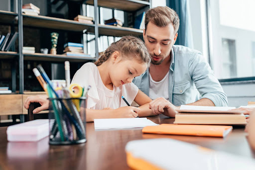 Father helping young daughter with homework; how divorce impacts a child’s education depends on numerous factors.