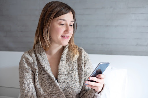 Young woman checking notifications on her phone during divorce; social media mistakes.