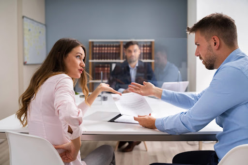 A divorcing couple discussing a settlement with a mediator via divorce mediation.