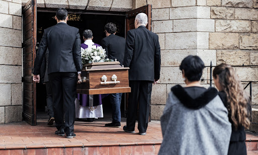 Pallbearers carrying a casket into a church; unexpected funeral when one spouse dies during divorce.